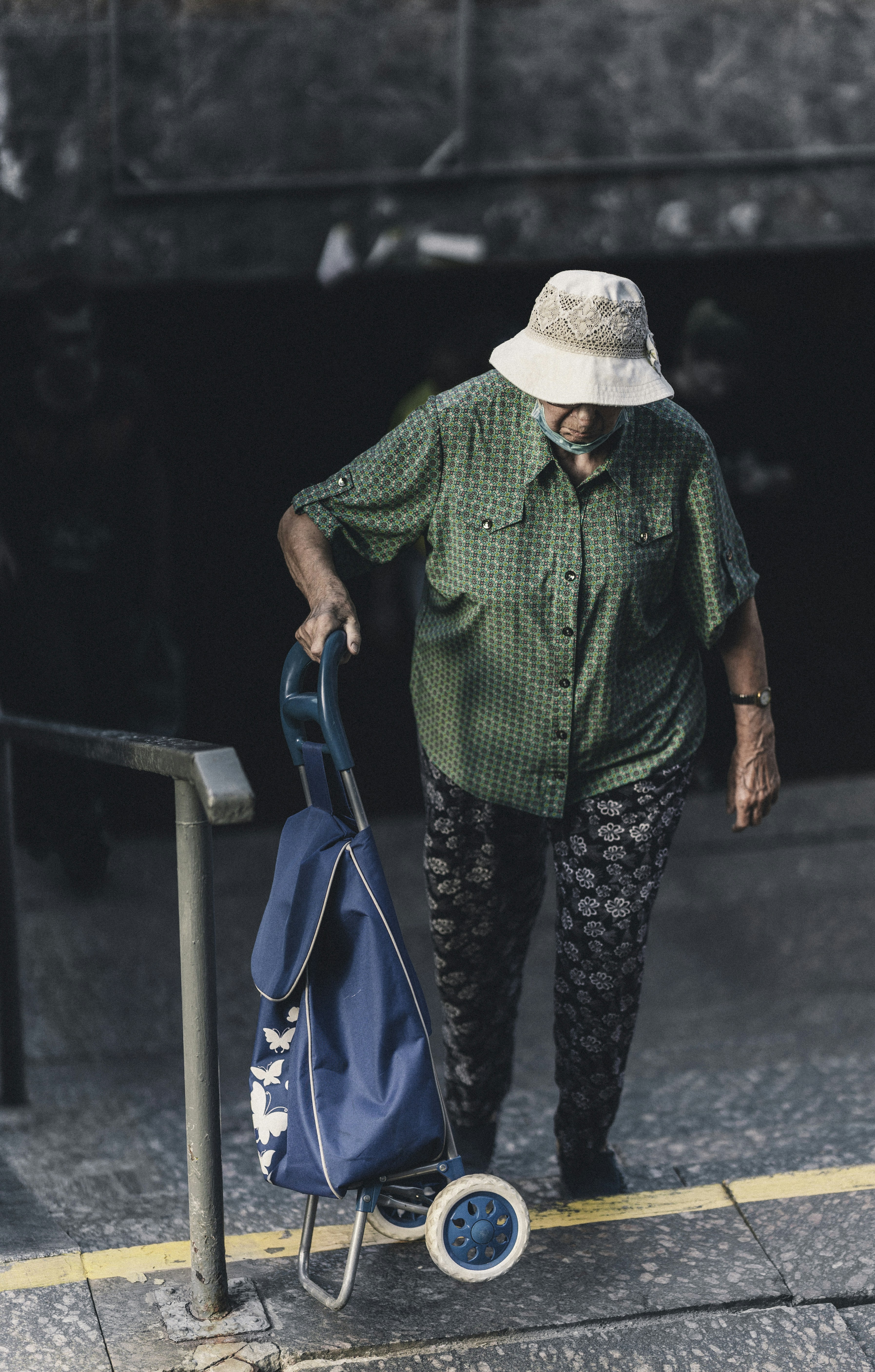 7 Travel Outfits That Stay Wrinkle-Free and Photo-Ready All Day – woman in green and black dress shirt and white hat holding blue umbrella