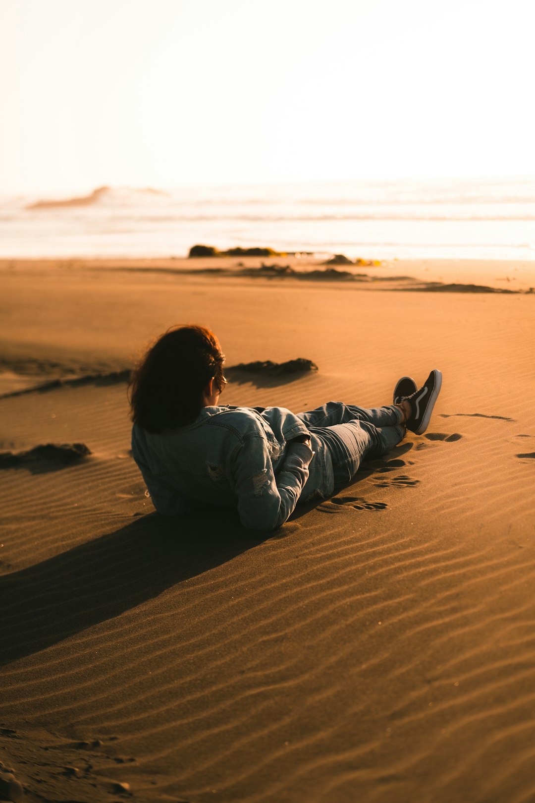 boy in gray hoodie lying on brown sand during daytime