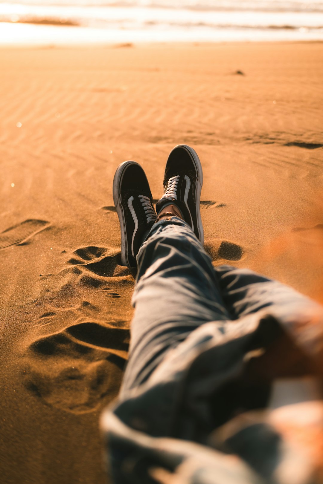 person in black and white sneakers on brown sand