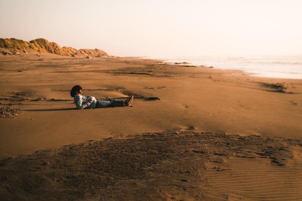 man in black and white jacket lying on brown sand during daytime