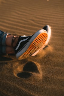 A pair of worn barefoot Aussie running shoes resting on sunlit red Australian earth.