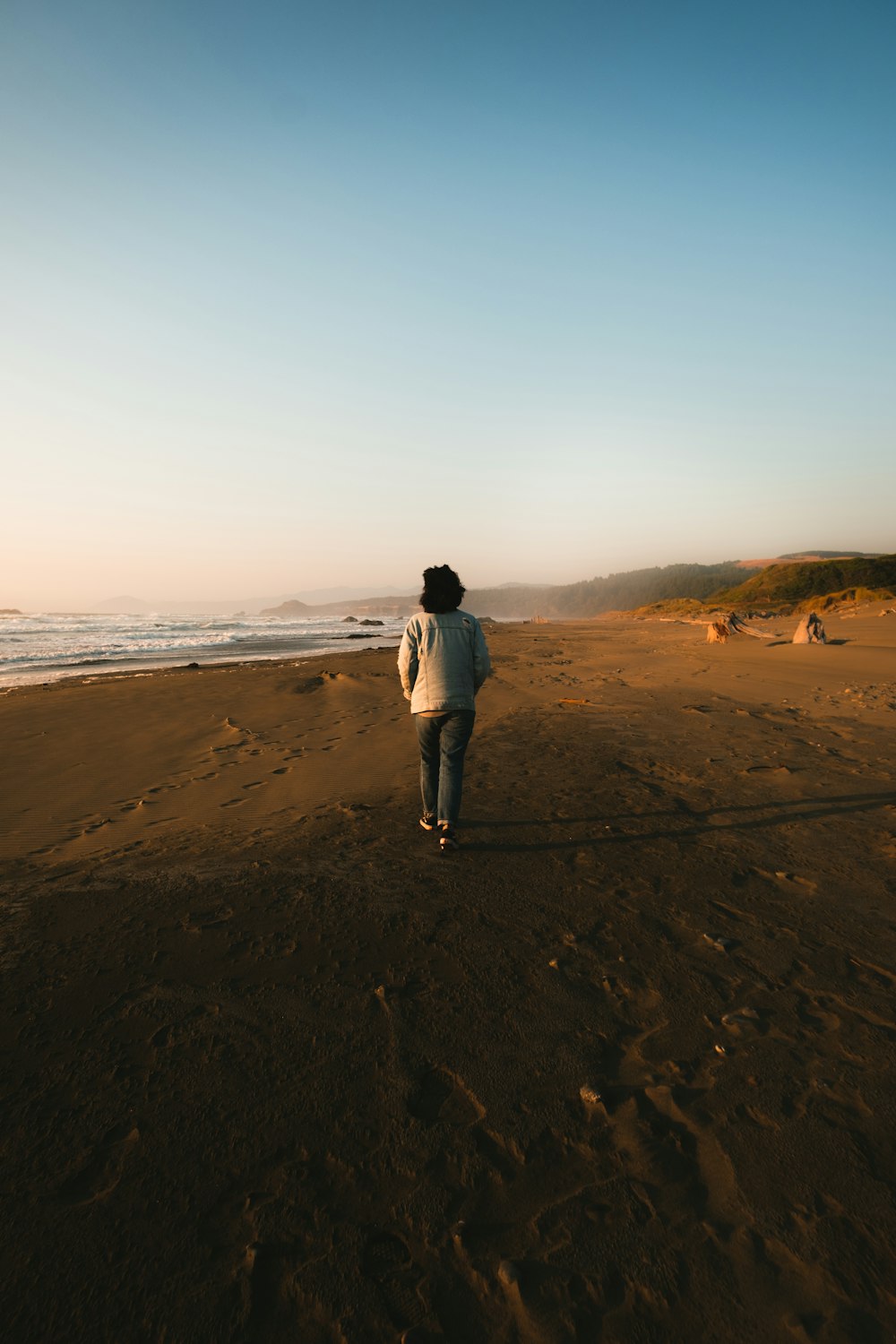 person in white jacket walking on brown sand during daytime