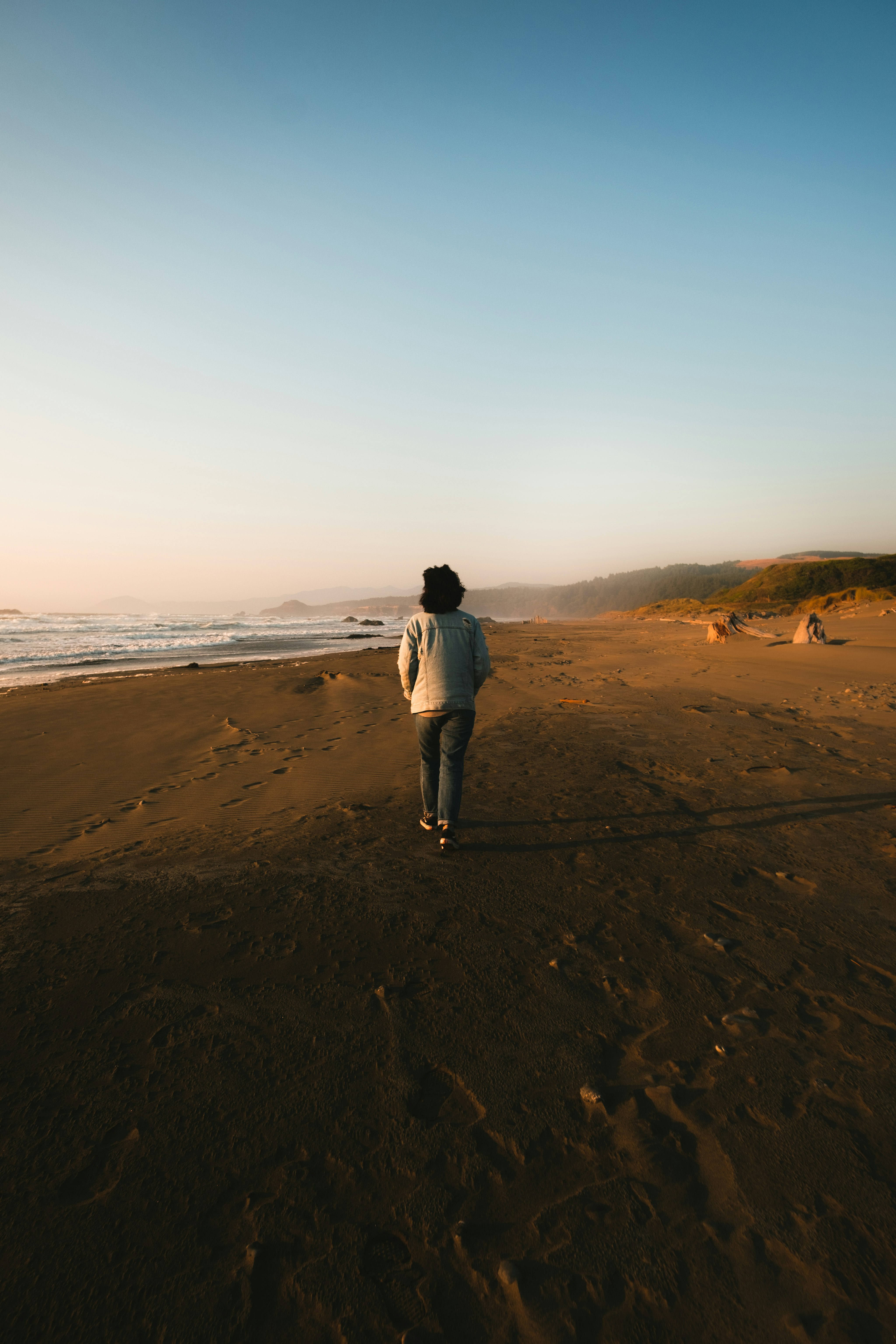 person in white jacket walking on brown sand during daytime
