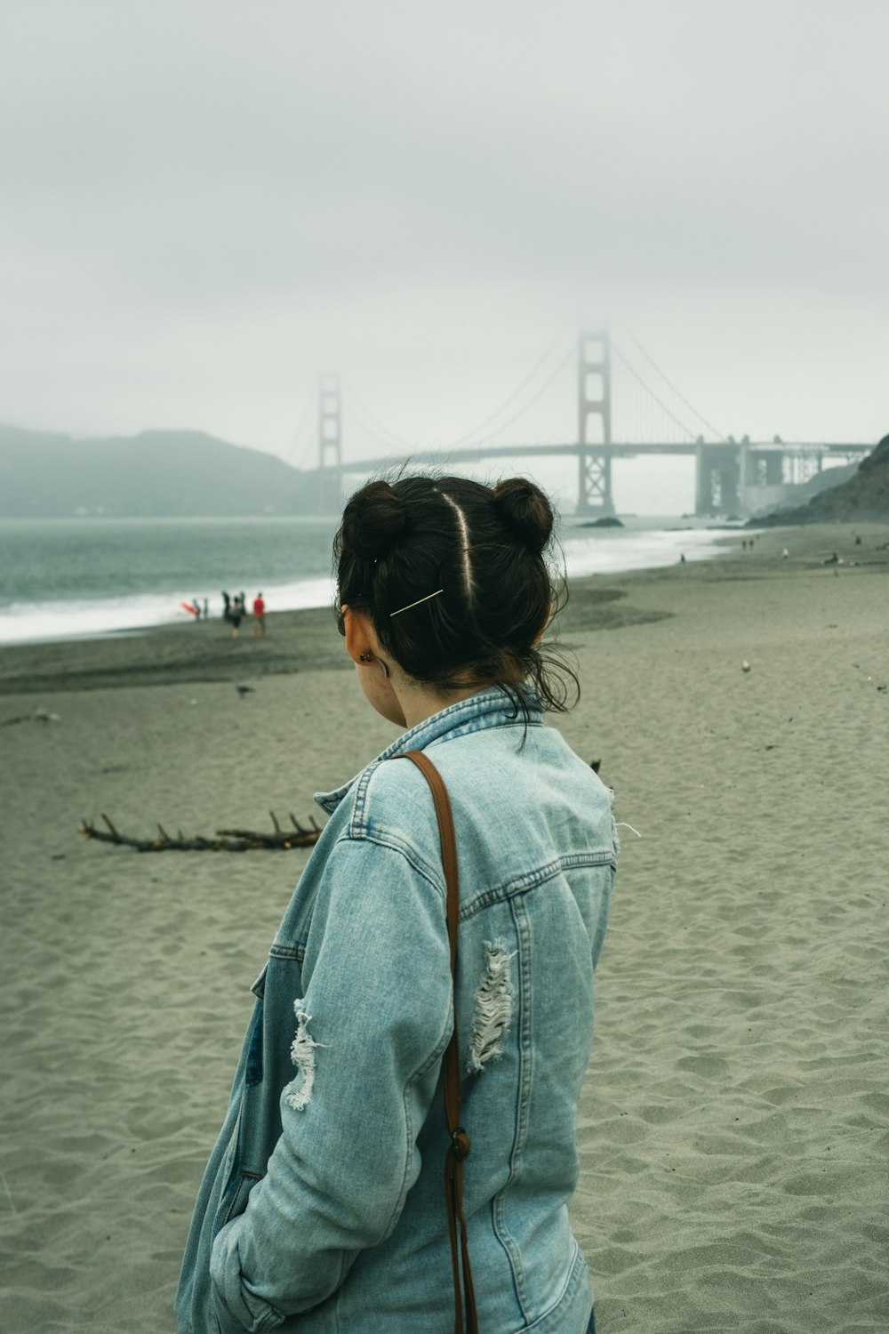 woman in blue denim jacket standing on beach during daytime