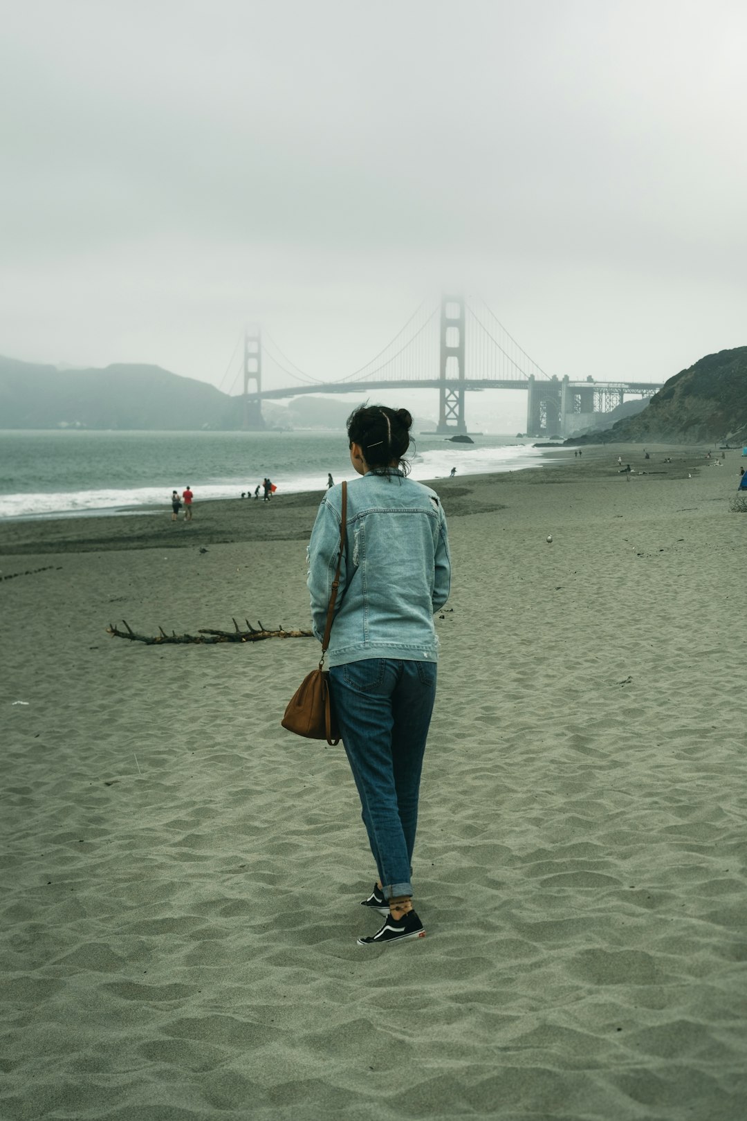 woman in blue hoodie standing on beach during daytime