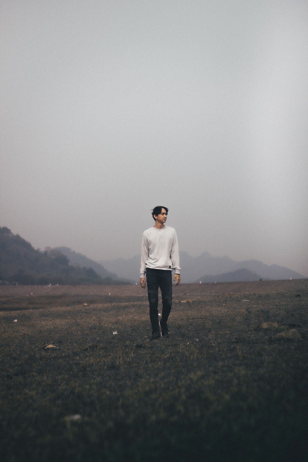 man in white long sleeve shirt standing on green grass field during foggy weather