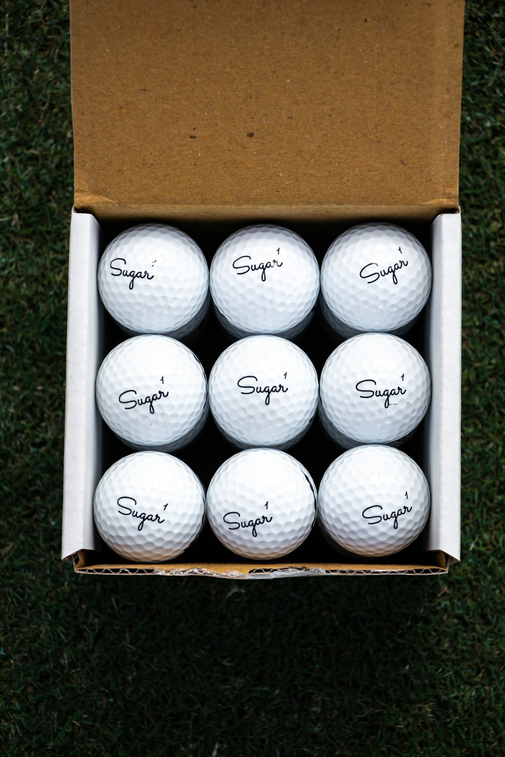 white golf balls in brown box