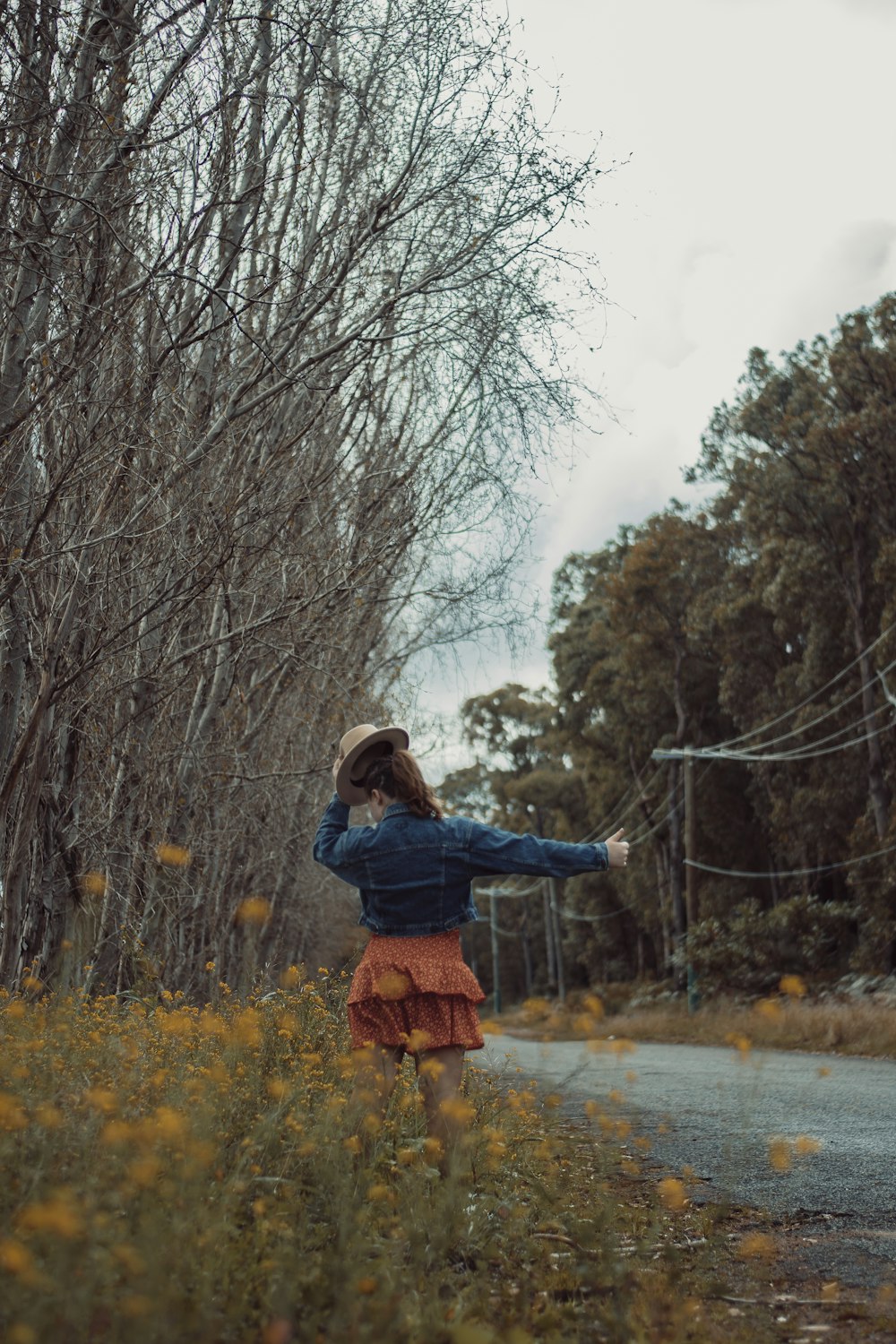 woman in blue jacket and brown pants standing on road during daytime