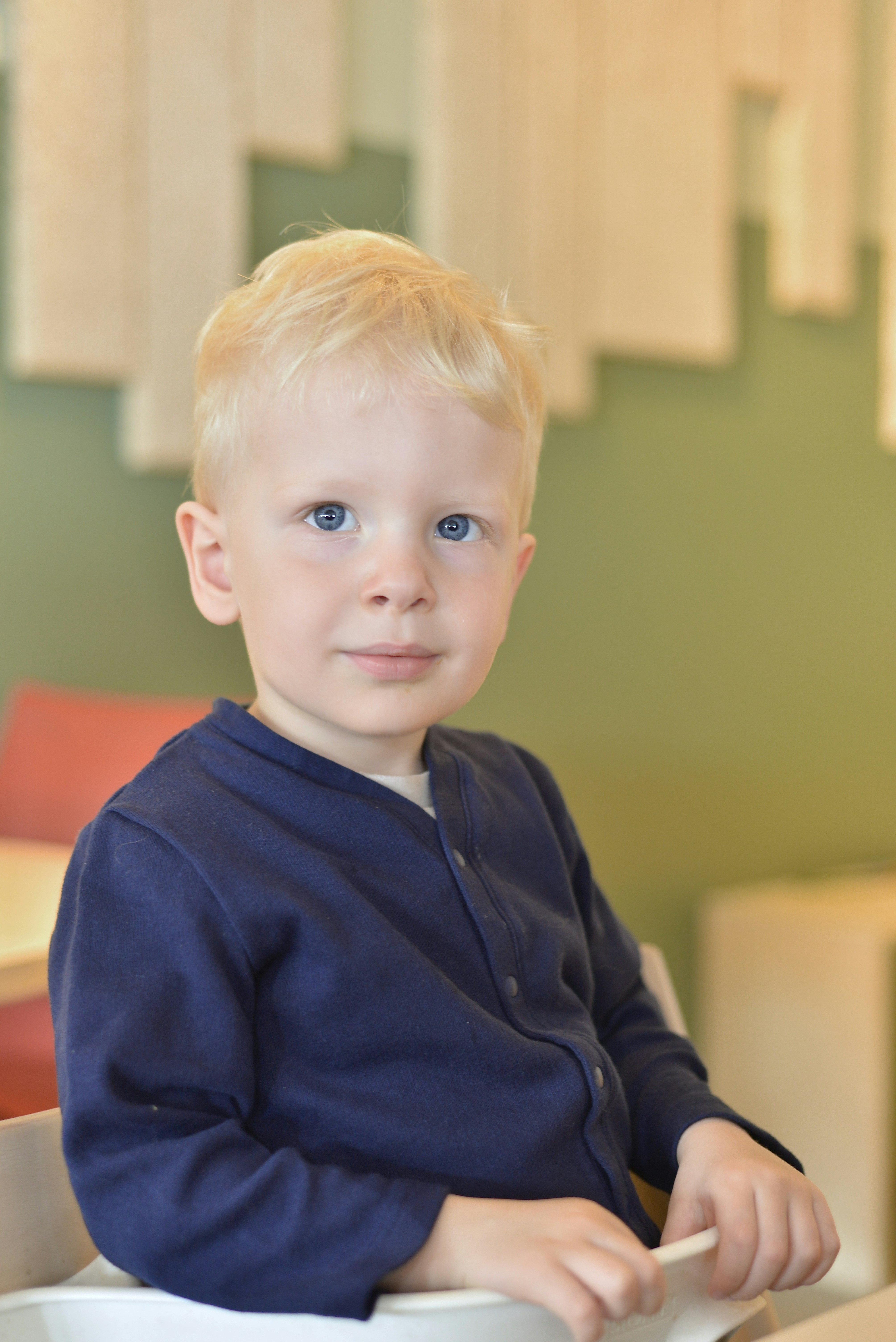 an adorable and well behaved child sits and awaits his lunch.