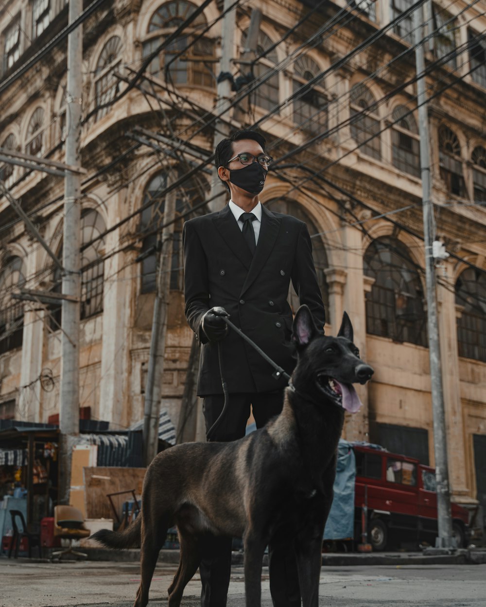 man in black coat standing beside black short coat large dog