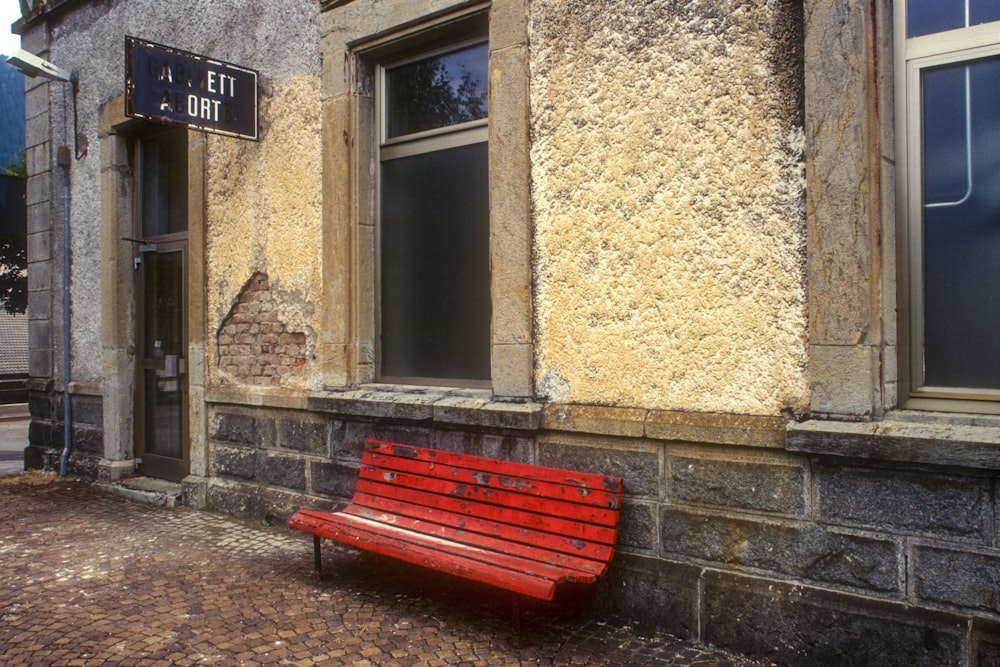 red wooden bench beside brown concrete wall