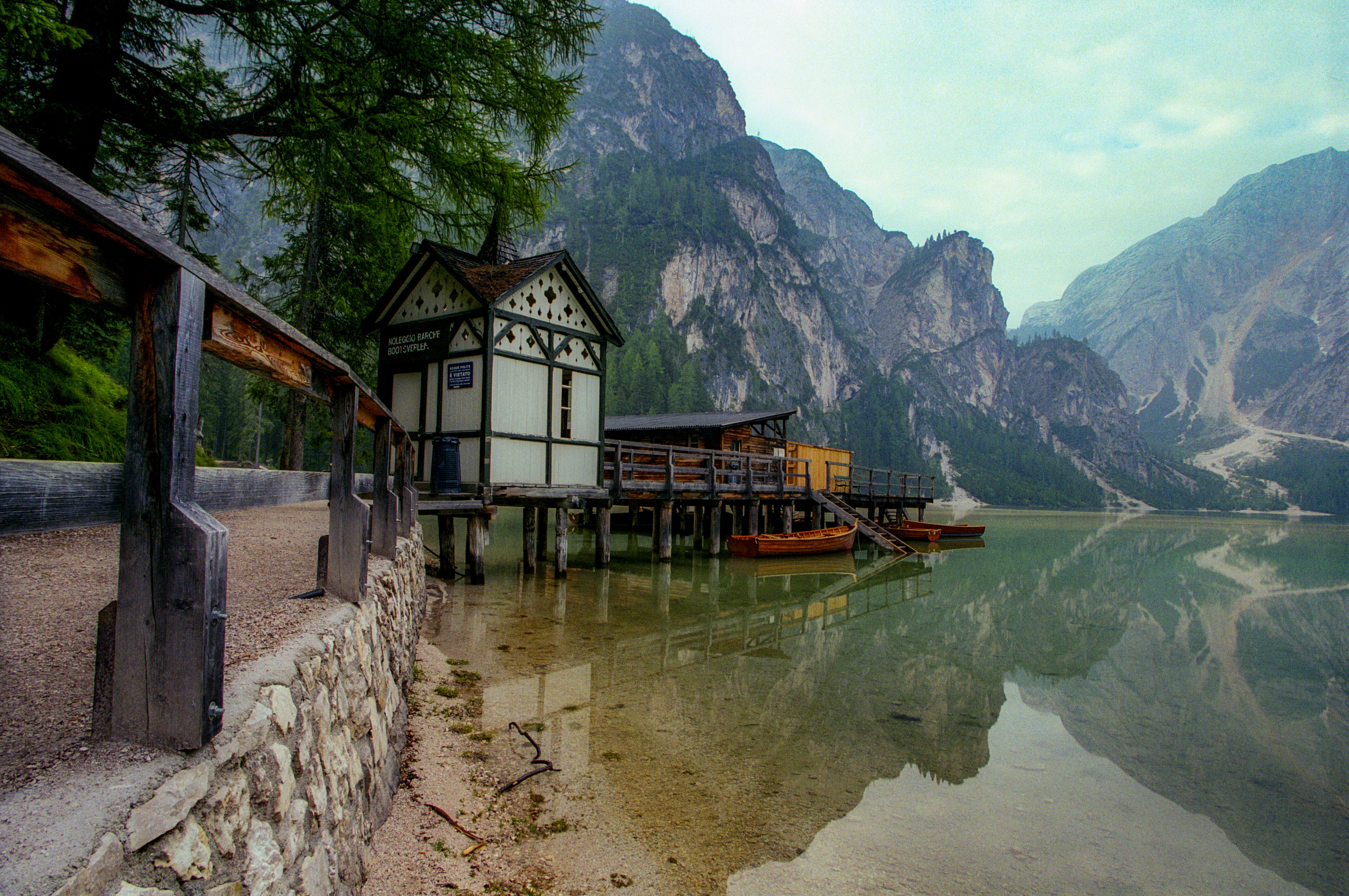 white and brown wooden house near lake and mountain during daytime