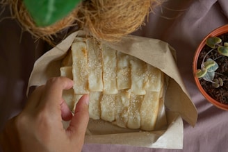 person holding brown bread on brown paper bag