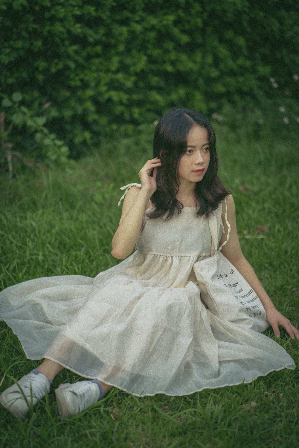 Muchacha en vestido blanco sentada en el campo de hierba verde durante el día