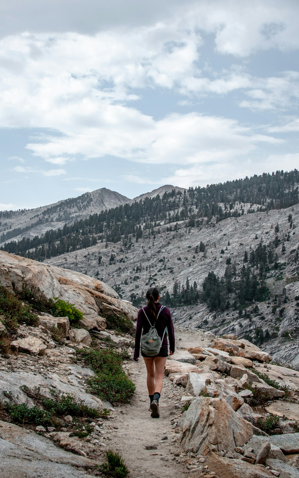 man in black jacket standing on rocky hill looking at mountains during daytime