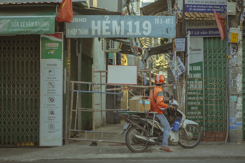 man in orange jacket riding on bicycle during daytime