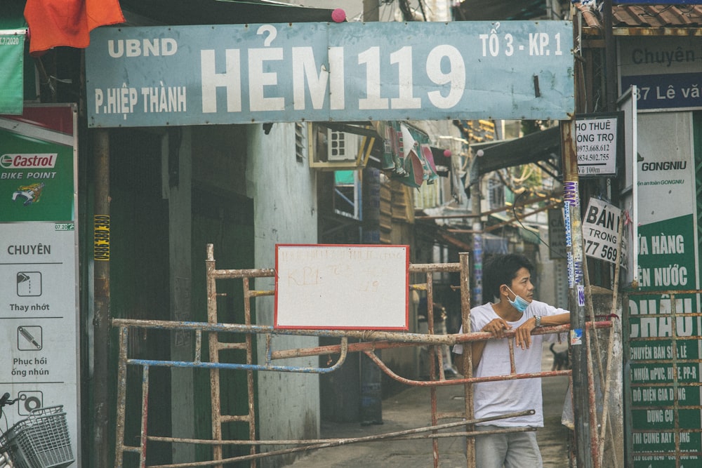 man in white dress shirt and blue denim jeans standing beside red and white signage during