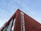 A red brick building with large white lettering in both Chinese and English, featuring the words 'Shenzhen Nanshan Laixiang'. A logo appears on the top portion of the wall. The sky is clear and blue, providing a contrast to the building's vibrant color.