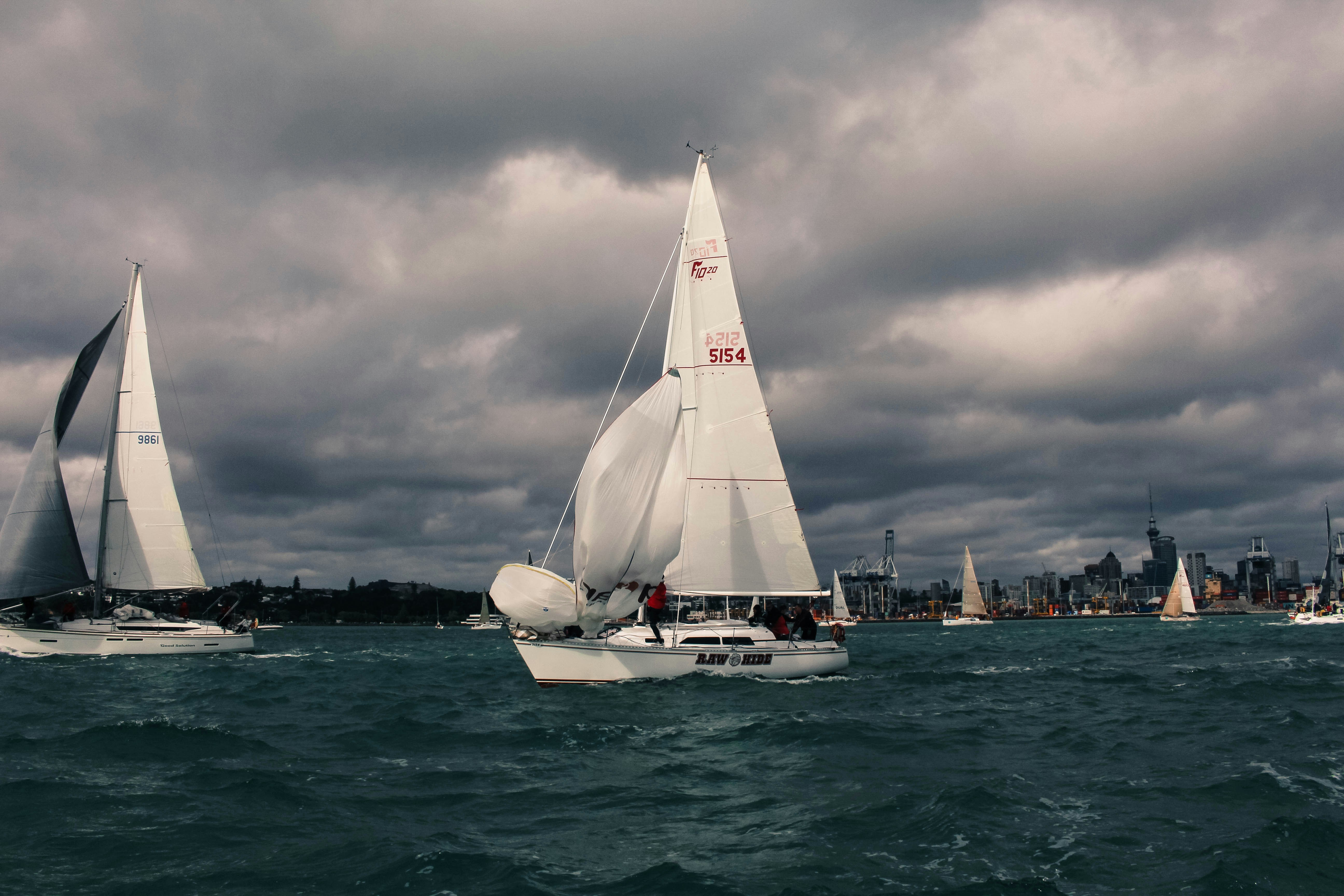 white sail boat on sea under gray clouds