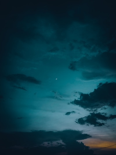 A moody night sky filled with shimmering stars and a glowing crescent moon.