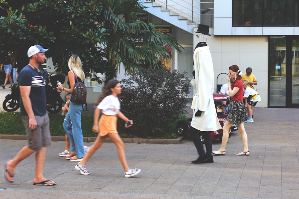 woman in white shirt walking on sidewalk during daytime