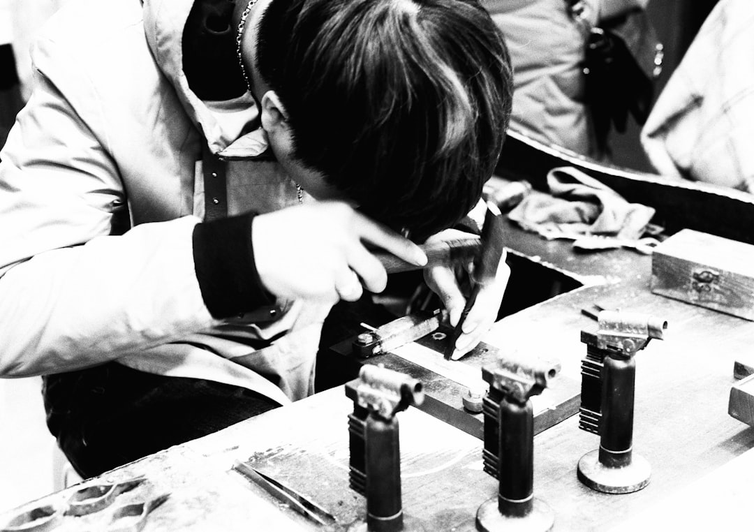 grayscale photo of man in white long sleeve shirt holding black metal tool