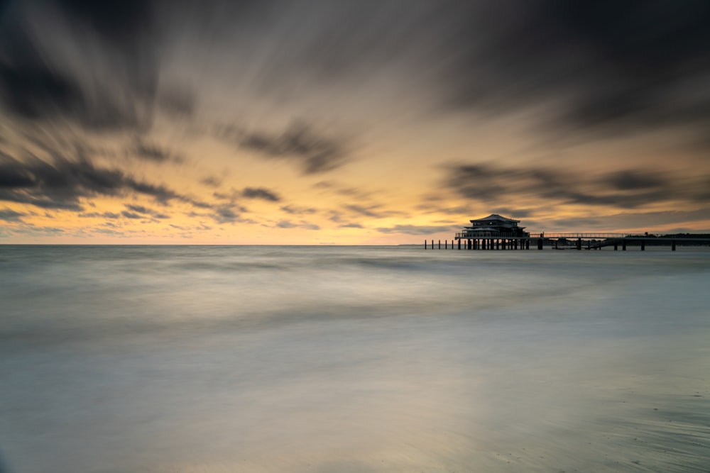a long exposure photo of a pier at sunset