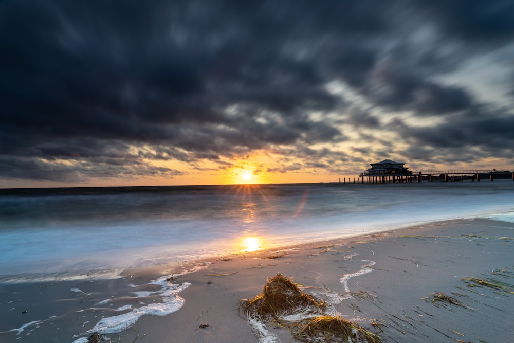 the sun is setting over the water at the beach