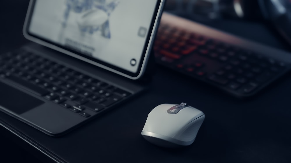 black and white logitech cordless computer mouse beside black laptop computer