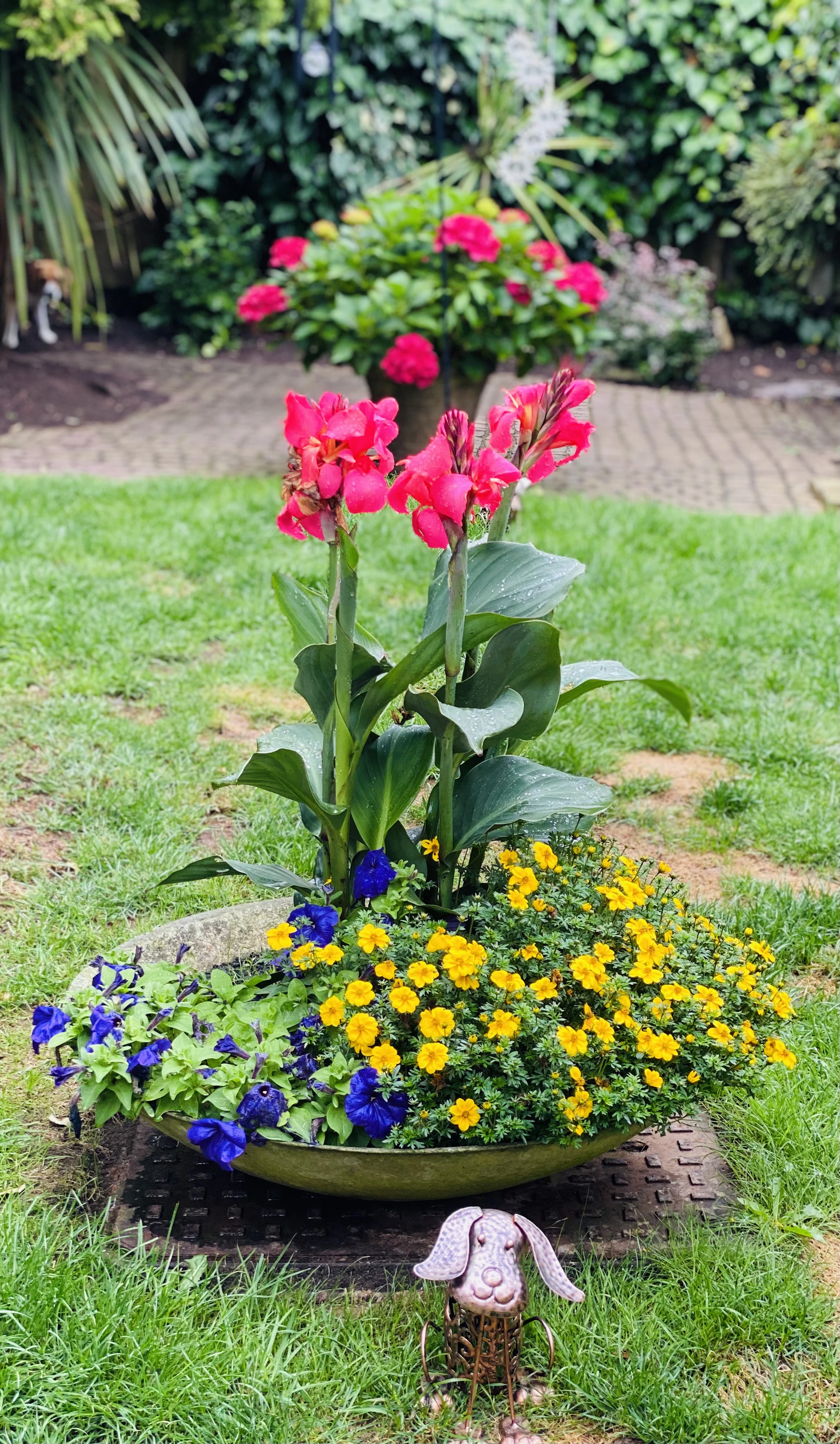 Handcrafted iron garden planter with intricate floral patterns, placed in a sunny backyard.