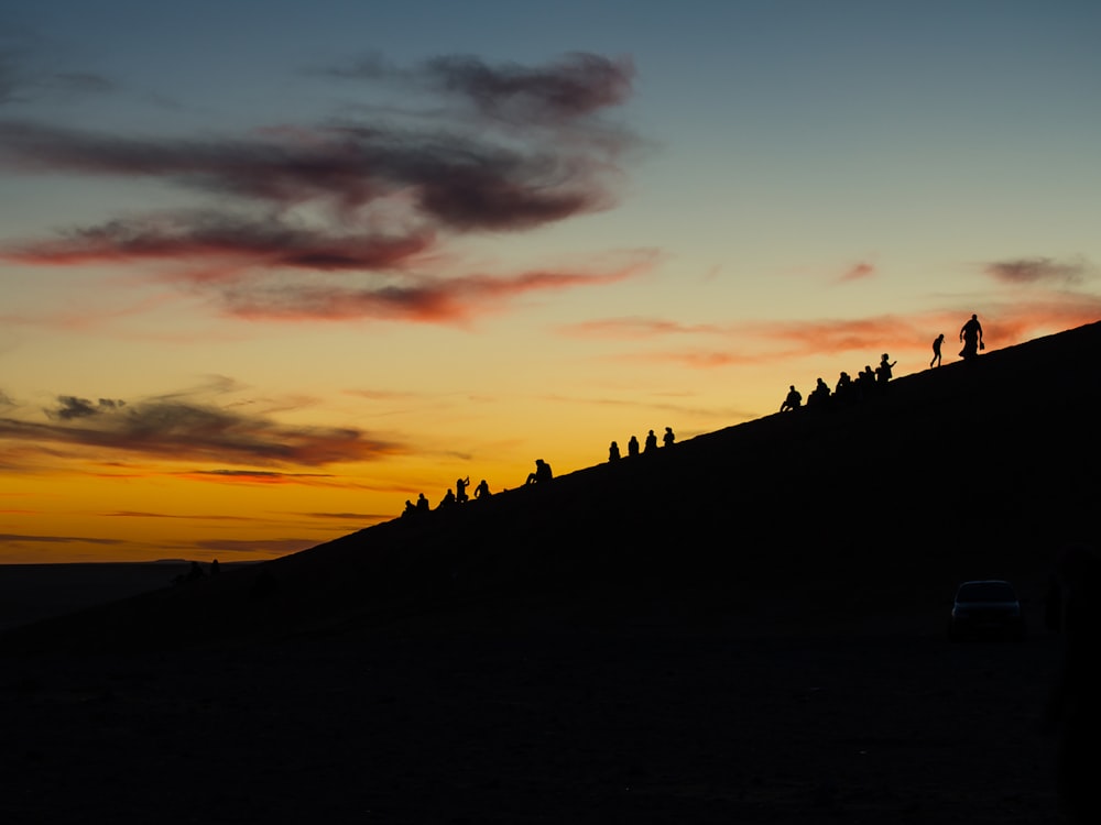 silhouette of people on hill during sunset
