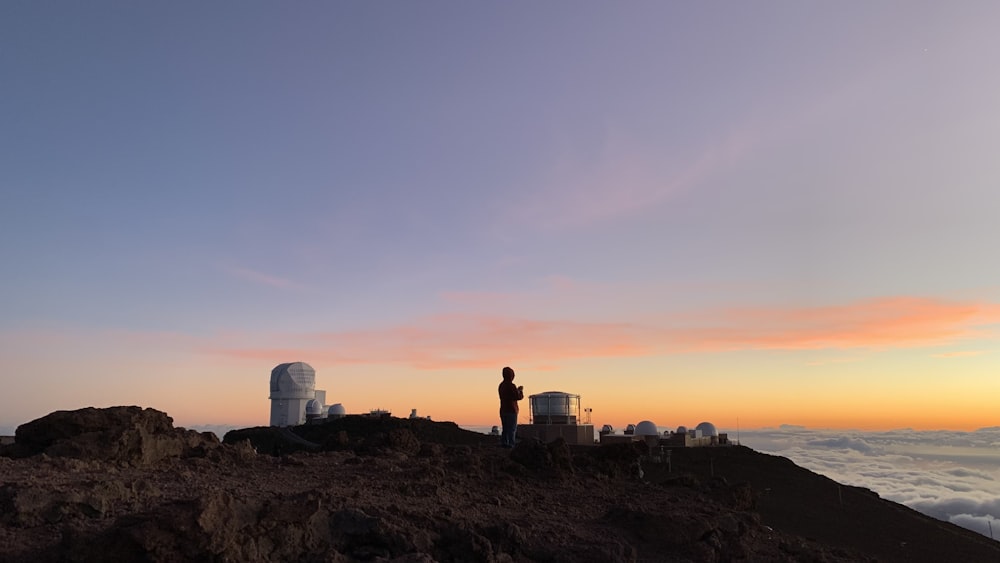 Silueta del hombre de pie sobre la roca durante la puesta del sol