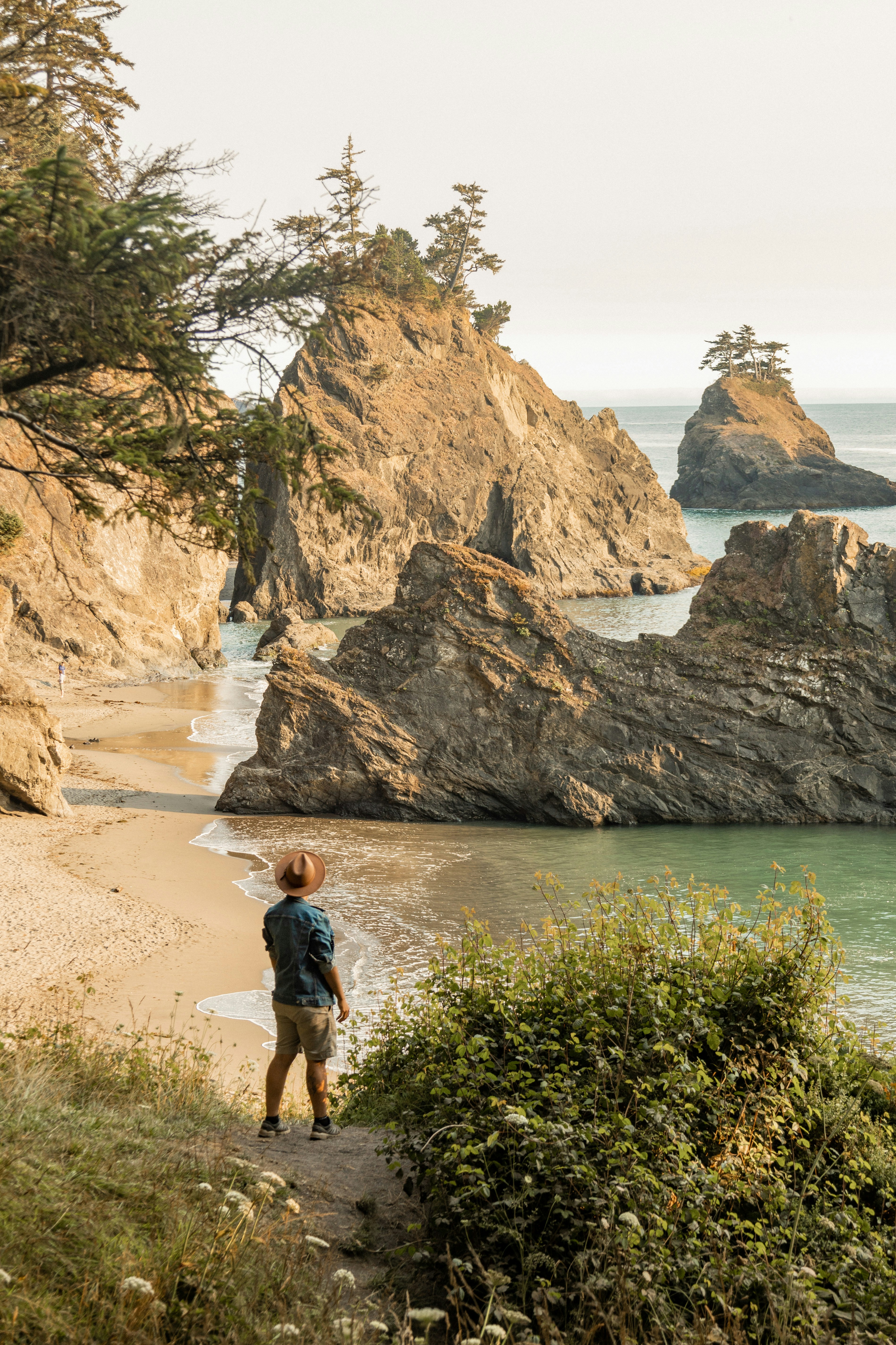 Femme en débardeur noir et short noir debout sur le sable brun près du plan d’eau