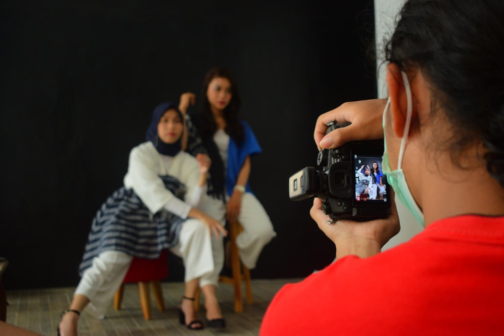 woman in red shirt holding black camera