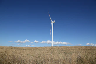 Wind turbine installed on a green farm field under a bright sky.