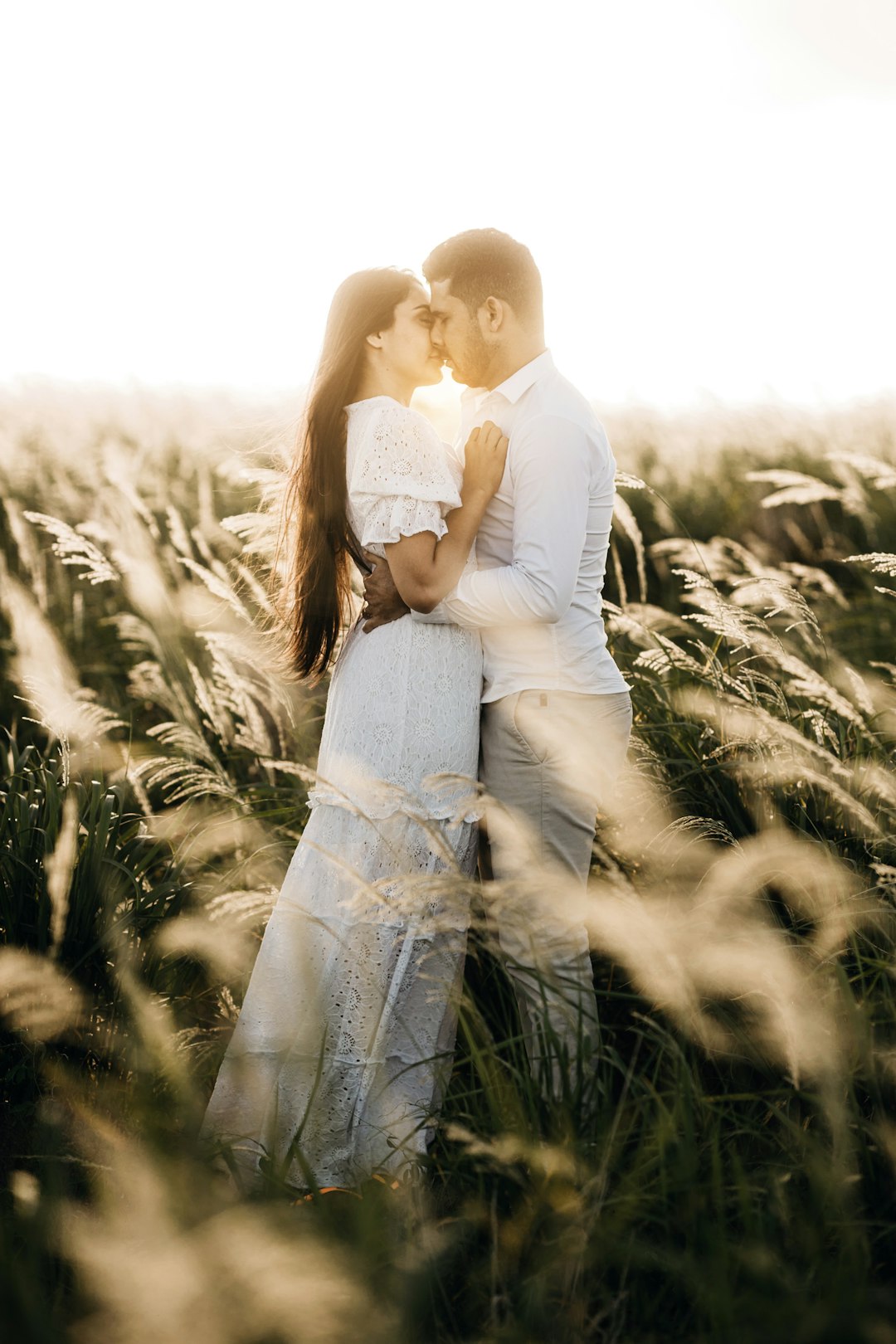 man and woman kissing on grass field during daytime