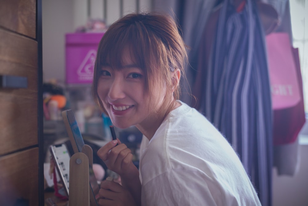 smiling woman in white dress shirt holding iphone