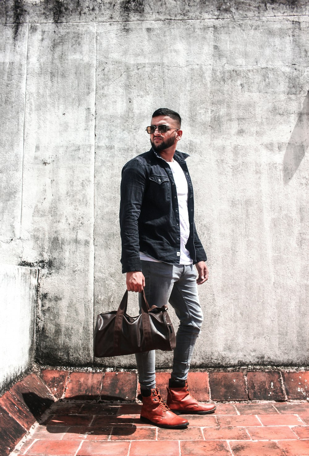 man in blue suit jacket and black pants holding brown leather handbag