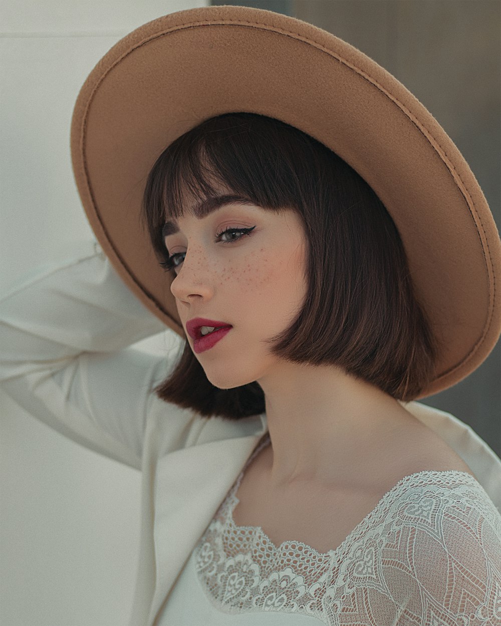 woman in brown hat and white lace top