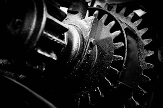 Close-up of interlocking metallic gears with digital code overlay in grayscale.