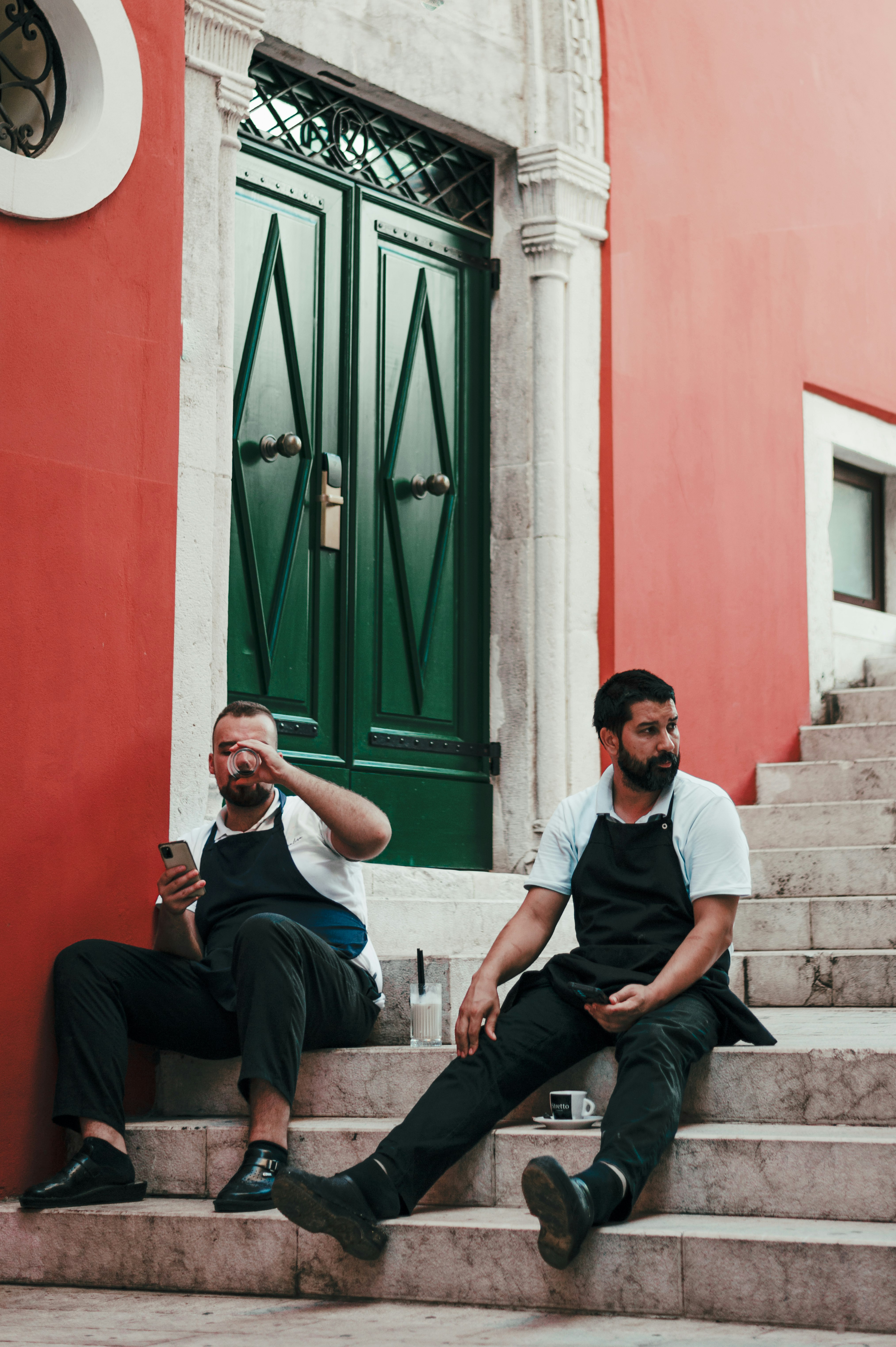 man in white crew neck t-shirt and black pants sitting on brown concrete bench