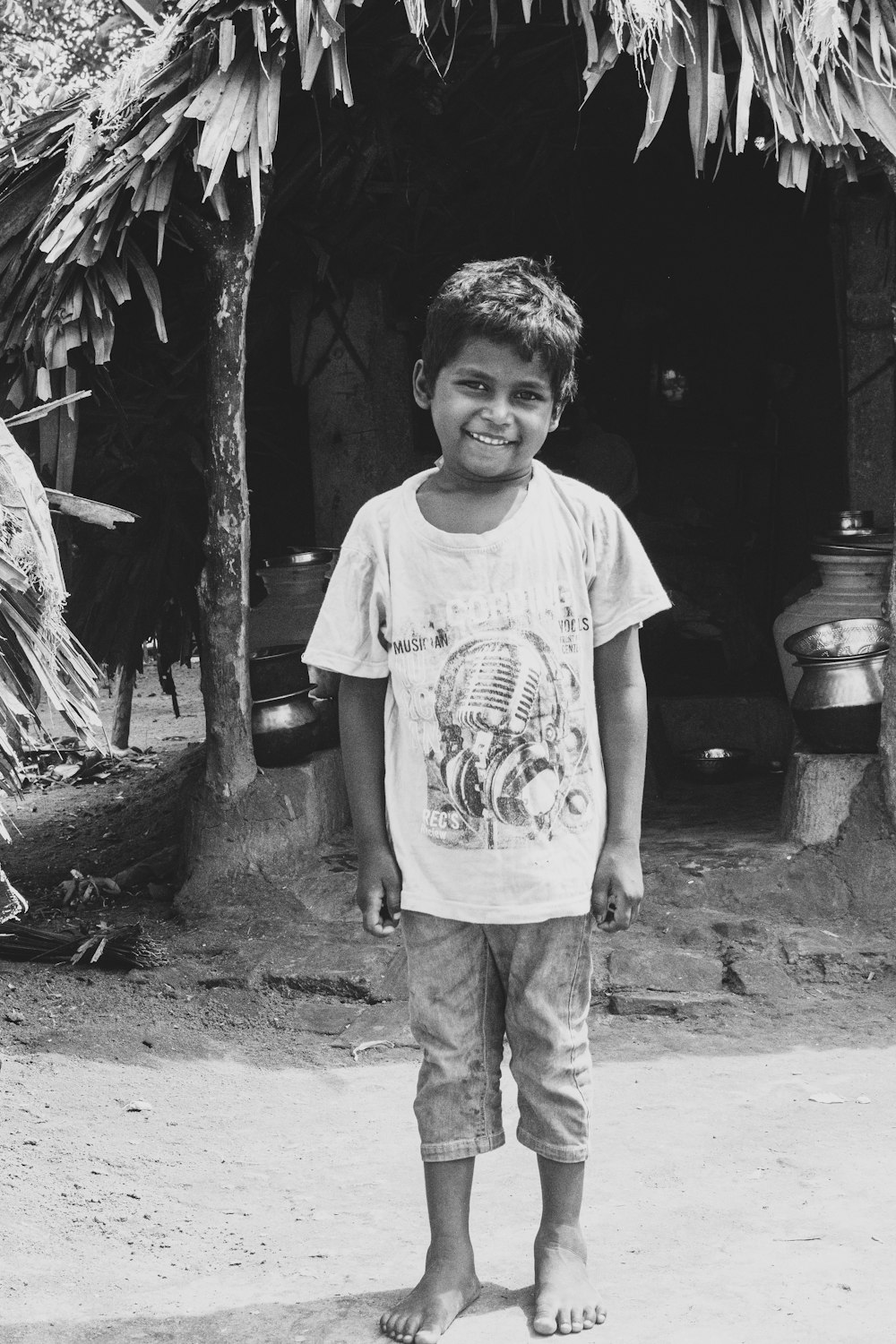 grayscale photo of boy in crew neck t-shirt and pants standing on ground