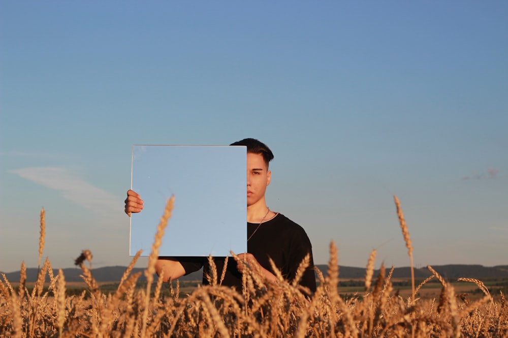 man in black crew neck shirt and black hat standing on brown wheat field during daytime