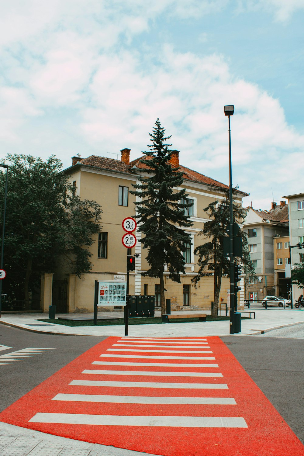 white and red pedestrian line near green trees and brown concrete building during daytime