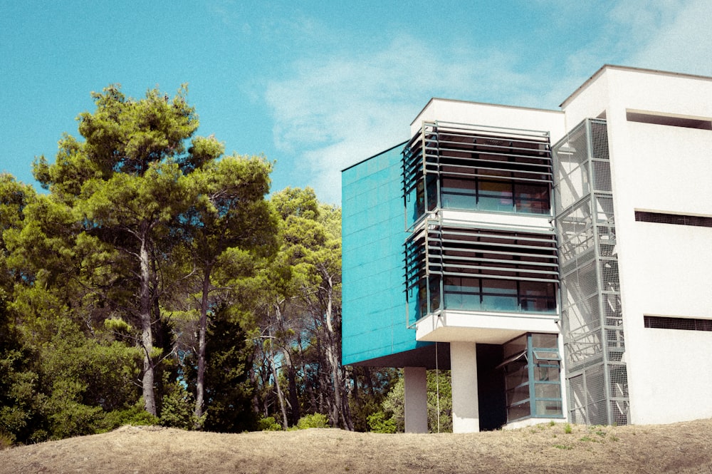 blue and white concrete building near green trees under blue sky during daytime