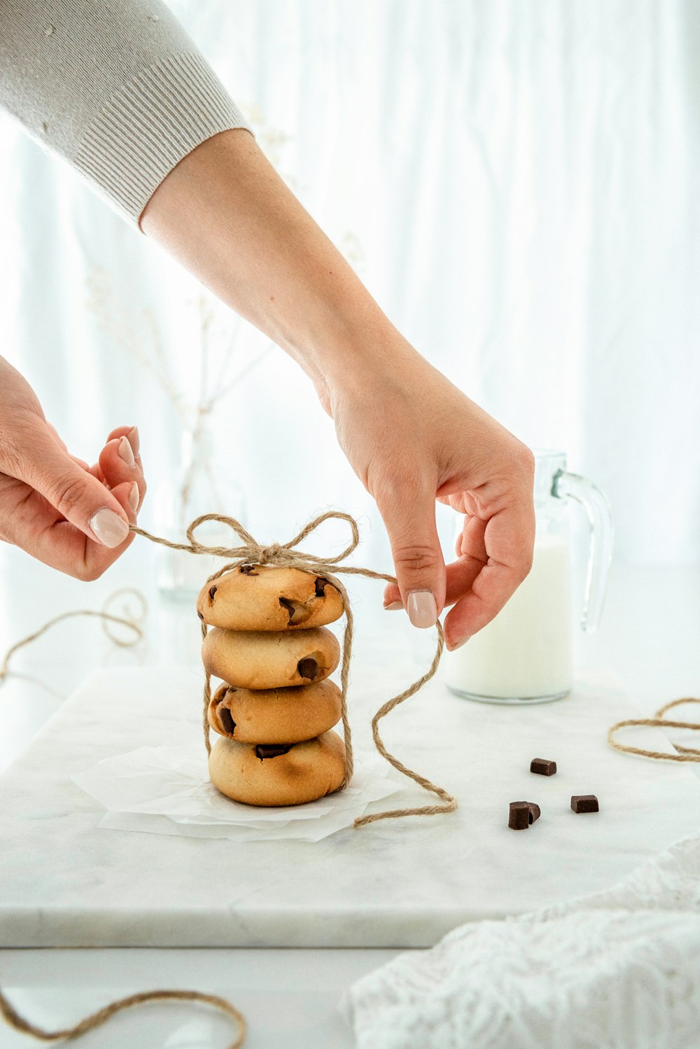 person holding white ceramic mug with brown cookies