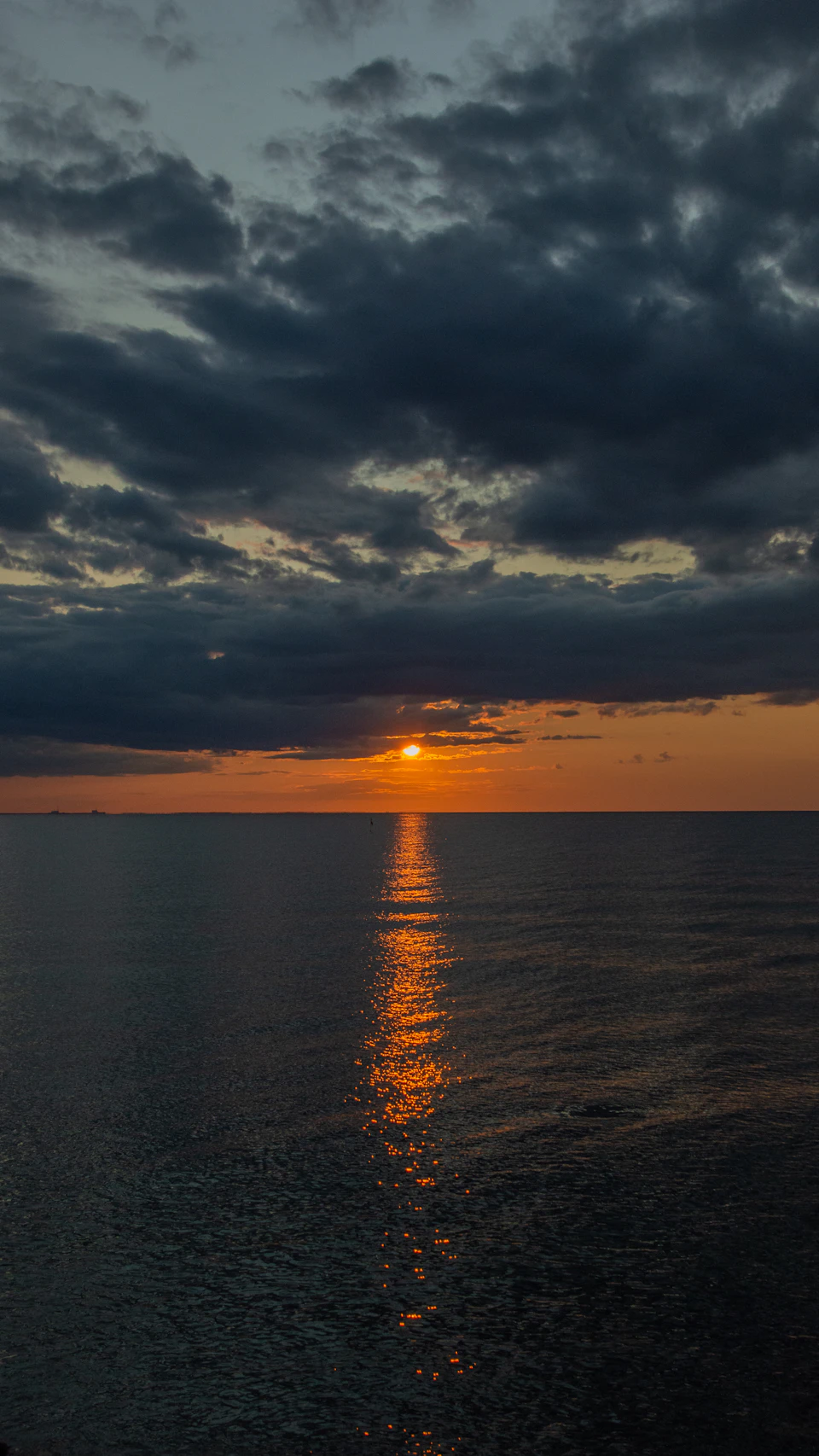 Sunset over ocean with warm glow on horizon and reflected vibrant colors in water