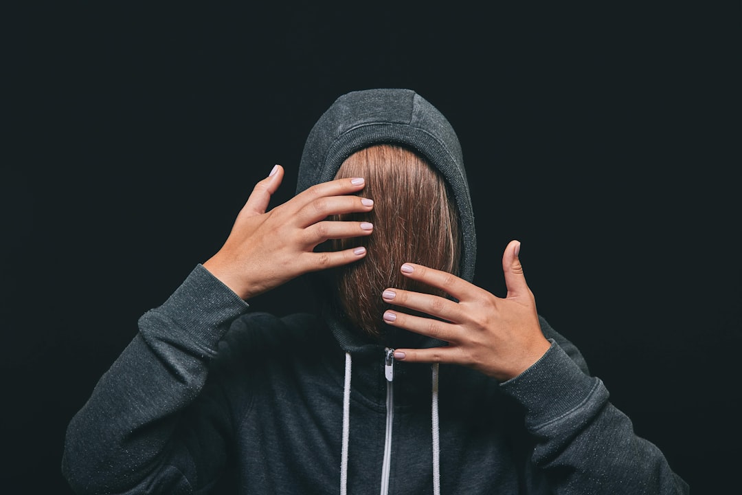 woman in black hoodie covering face with her hair