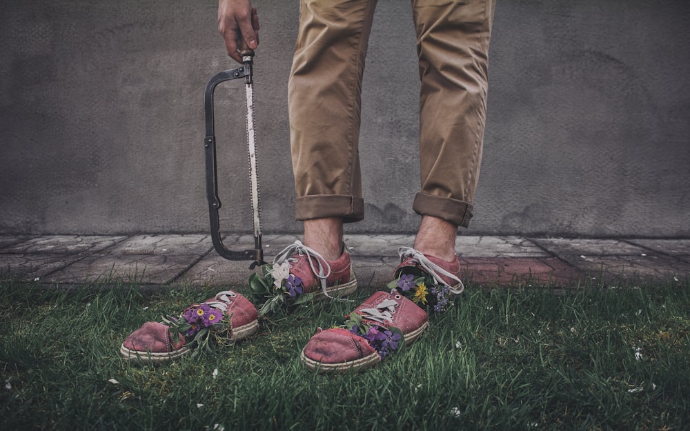 person in brown pants and red and green sneakers standing on green grass field