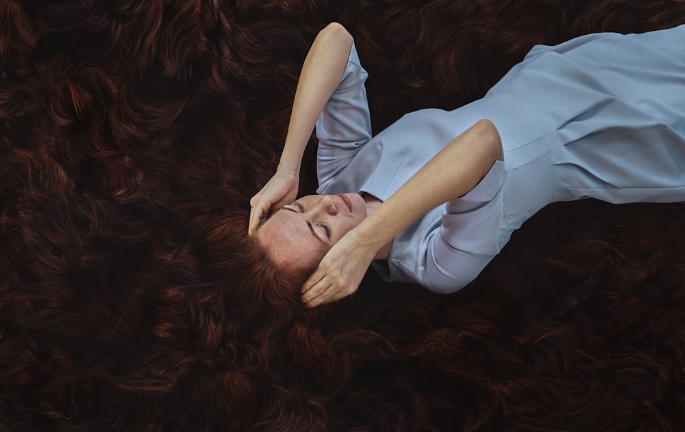 woman in white long sleeve shirt lying on brown dried leaves